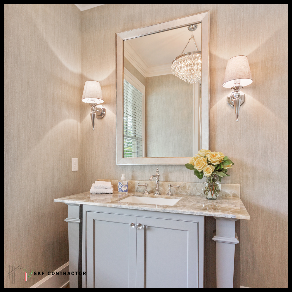 Grey shaker vanity with marble top, chrome faucet, framed mirror, wall sconces, and yellow roses