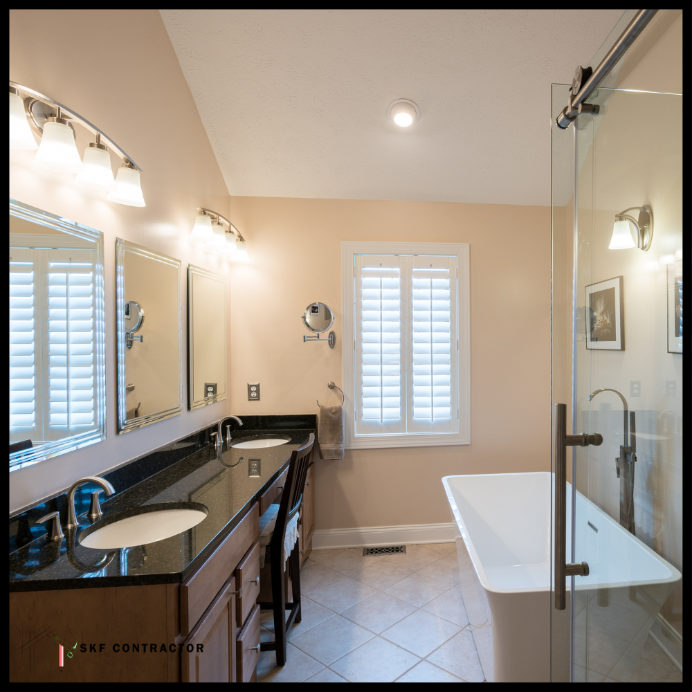Master bathroom with double granite vanity, freestanding soaking tub, glass shower, and plantation shutters.
