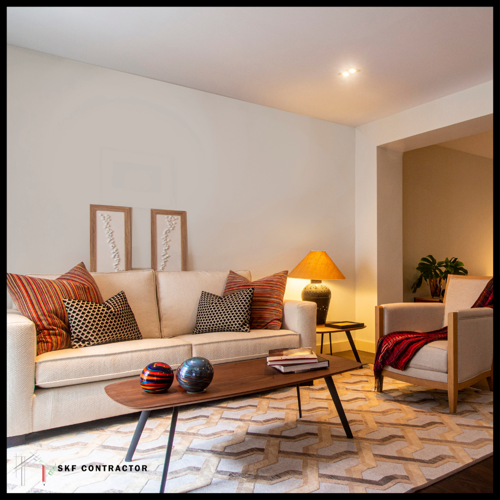 Mid-century cream sofa, ethnic cushions, oval walnut coffee table, amber lamp, and geometric patterned rug.