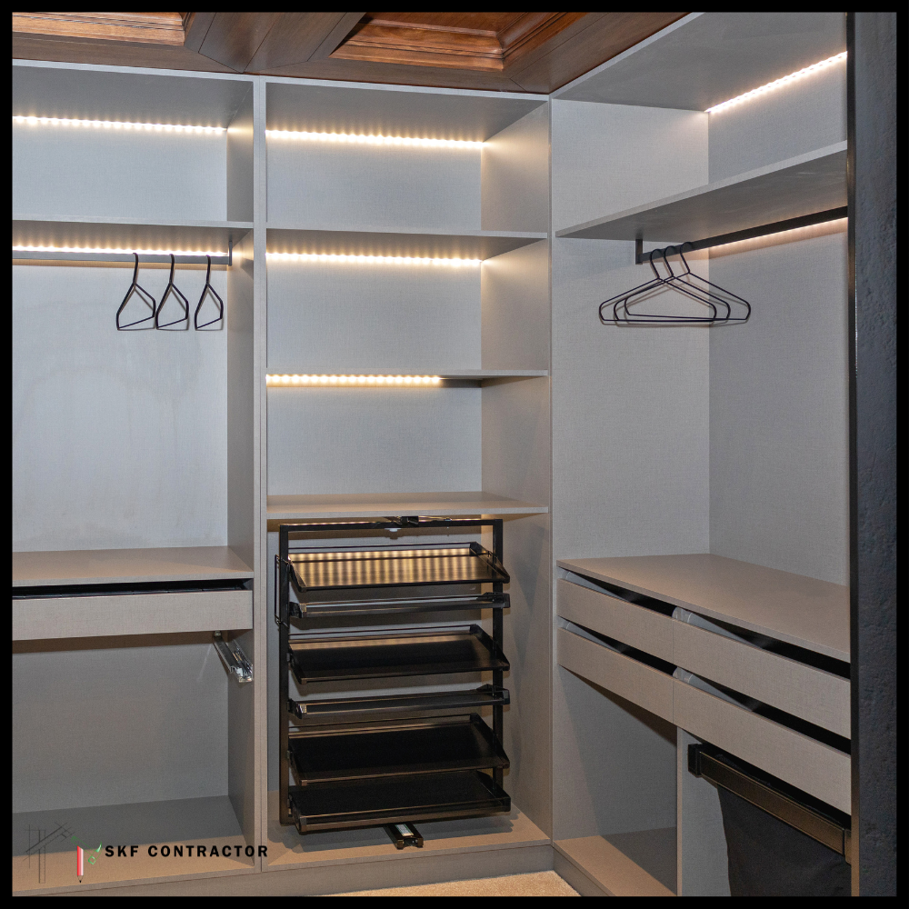 Walk-in wardrobe interior with LED shelf lighting, hanging rods, pull-out trays and drawers.