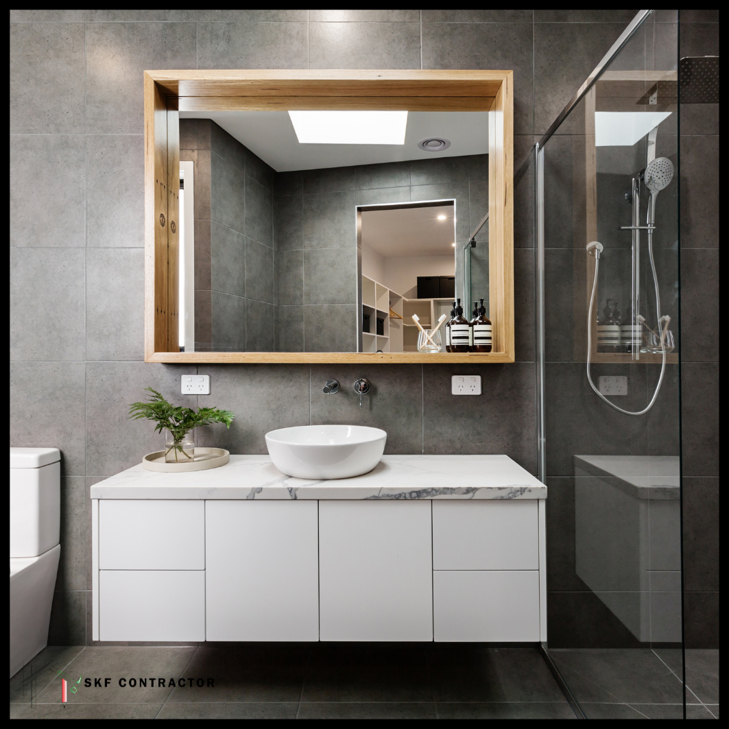 White floating vanity, marble top, round vessel sink, oak backlit mirror, grey tiles, glass shower.