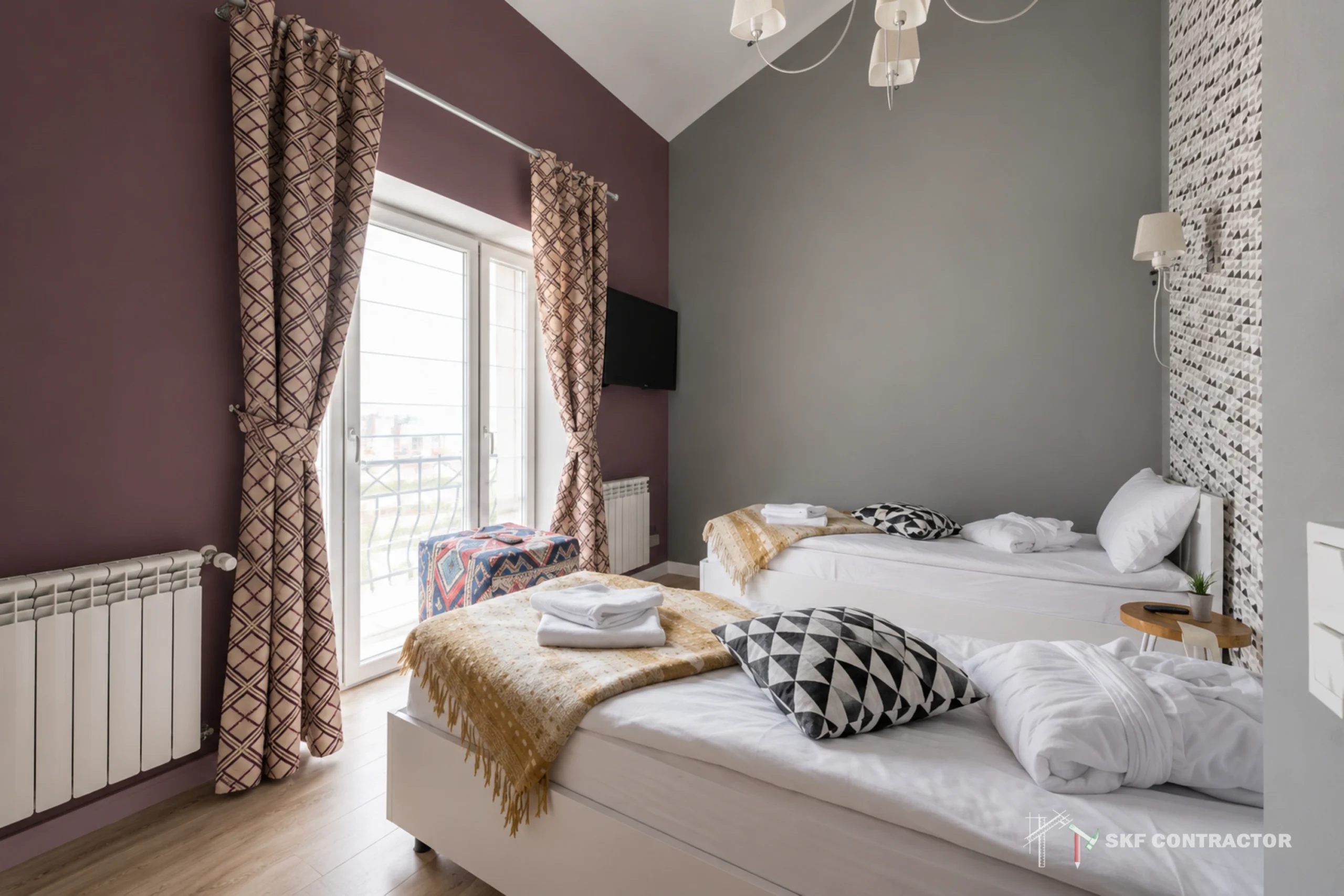 Bright modern bedroom with two white beds, patterned pillows, textured curtains, gray and plum walls, and daylight from a balcony door.